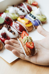 Male hand taking delicious sweets with glaze, colorful dessert