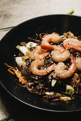 Delicious meal with shrimps in black plate, traditional Asian  food 