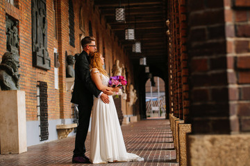 Beautiful wedding couple posing in city, bride holding beautiful bouquet of flowers in hands