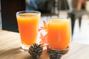 A glasses of ice orange juice on wooden table with pine cone