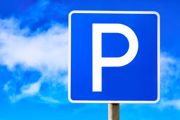 Blue parking sign against blue cloudy sky background.