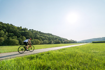 Rennradfahrer fährt Feldweg im Frühling entlang