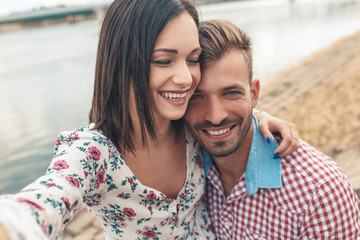 Obraz premium Beautiful couple enjoying time together outdoor, young girl making selfie with phone.