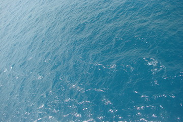 A view from the deck of the ship on a variety of shades of blue color of the sea surface under the rays of the sun, which are reflected from a small ripple.