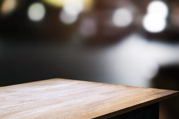 empty wood table top over blur night light in restaurant cafe background.