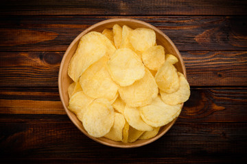 Potato chips in bowl on dark rustic wooden table