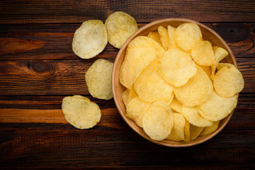 Potato chips in ceramic bowl on dark wooden table