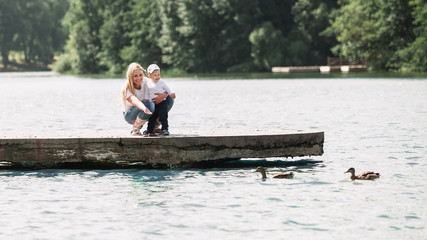Fototapeta na wymiar mom with her little son feeding wild ducks on a walk near the lake.