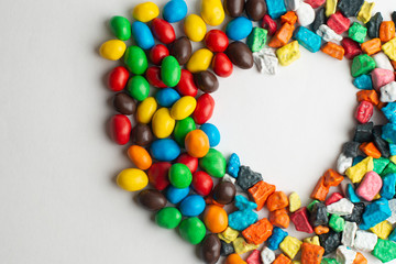 Colorful frame of multicolored candies on white background