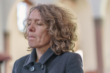 Religious devout woman praying alone in a church