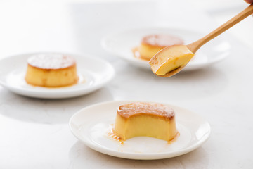 A bite piece of sweet creamy caramel custard in spoon and in plate