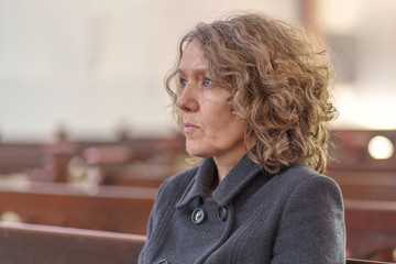 Religious woman sitting alone in a church pew