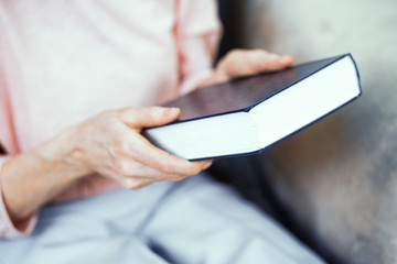 Blue Thick Book in the Hands of An Elderly Woman.