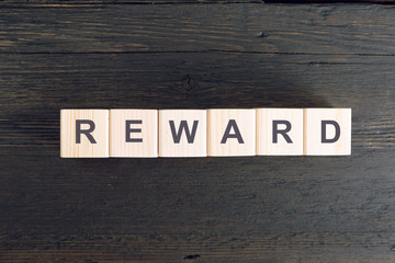 Word REWARD written on a wooden cube. Risk and reward concept