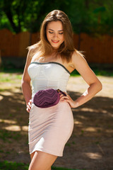 Closeup portrait of a happy young brunette woman in pink skirt and white corset