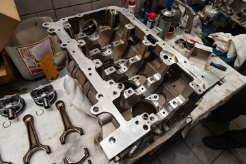 A four-cylinder engine dissembled and removed from car on a workbench in a vehicle repair workshop. Auto service industry.