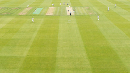 Young boys playing test cricket with a red ball dressed in white