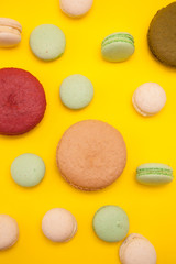 Delicious big caramel macaroon flavour next to cherry macaroon over yellow background