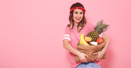 Portrait of a girl with a bag with fruit isolated on a pink background