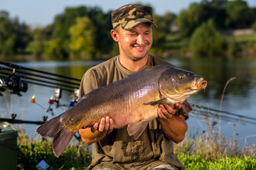 Happy angler with carp fishing trophy