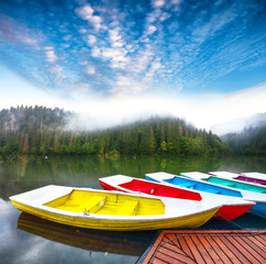 Boats on majestic mountain lake Lacul Rosu or Red Lake or Killer Lake