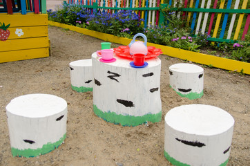 table with set of children's dishes for tea drinking and seat made of wooden chocks