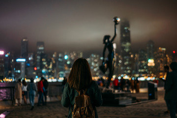 Fototapeta premium Young woman traveler is visiting at Avenue of Stars at night in Hong Kong China