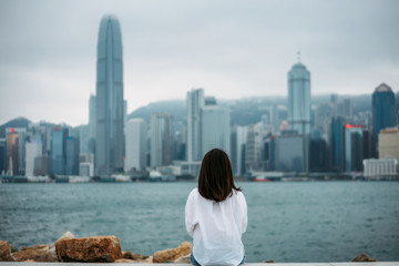 Young woman traveler is sitting looking cityscape view of Hong Kong China
