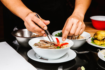 Traditional oriental cuisine of  Vietnam. Cook is cooking Pho bo soup with rice noodles, beef, pepper, wheat germ, greens