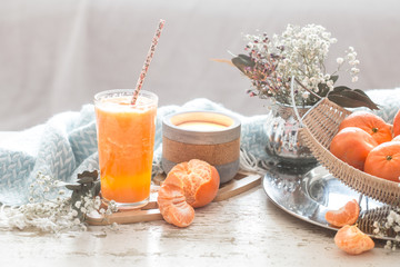 Freshly-grown organic fresh orange juice in the interior of the house, with a turquoise blanket and a basket of fruit
