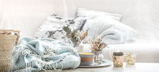 Home decorations in the interior. A turquoise blanket and wicker basket with a vase of flowers and candles