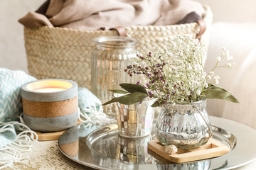 Home decorations in the interior. A turquoise blanket and wicker basket with a vase of flowers and candles