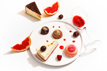 Gourmet desserts and grapefruit slices on a white plate. Top view.