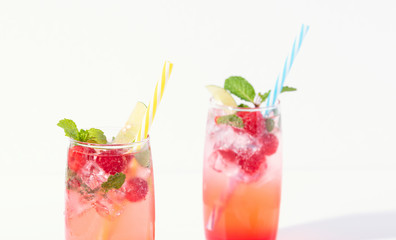 iced red raspberry punch cocktail with lime in glass on white background. summer drink.