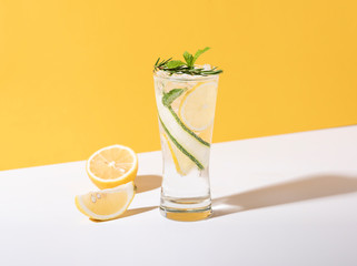 Mojito cocktail with lemon and mint in glass on yellow background. summer drink.
