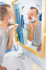 Guy shaving his beard in bathroom