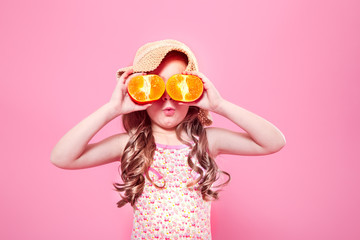 Funny little girl with citrus fruit on color background