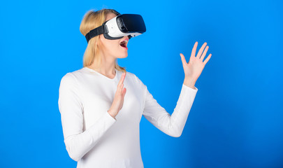 Cheerful smiling woman looking in VR glasses. Confident young woman adjusting her virtual reality headset and smiling. Amazed young woman touching the air during the VR experience.