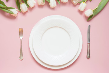Elegant table setting with white tulip on pink table. Romantic spring dinner.