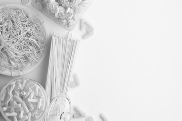 Monochrome composition of dry and boiled pasta and spaghetti on a white background. Banner with copy space for text. A set of food on the top view. 3D rendering.