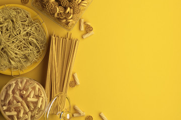 Fototapeta na wymiar Monochrome yellow composition of dry and boiled pasta and spaghetti on a yellow background. Banner with copy space for text. A set of food on the top view. 3D rendering.