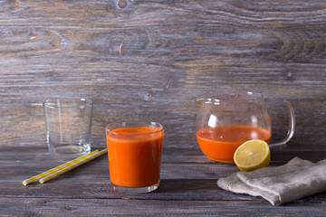 Fresh carrot juice in a glass on a wooden background