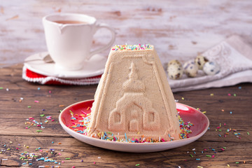 Traditional Russian Easter cottage cheese dessert, Orthodox Paskha, with boiled condensed milk on a wooden table