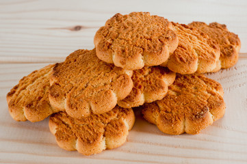 Tasty and beautiful cornflakes cookies among of corn flakes on a wooden table as background, top view