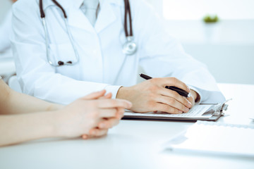 Fototapeta premium Doctor man and patient are discussing something, just hands at the table. Medicine and health care concepts