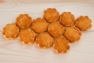 Tasty and beautiful cornflakes cookies among of corn flakes on a wooden table as background, top view