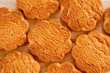 Tasty and beautiful cornflakes cookies among of corn flakes on a wooden table as background, top view