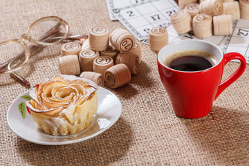 Board game lotto on sackcloth. Wooden lotto barrels and game cards with cup of coffee and homemade cookie on plate.