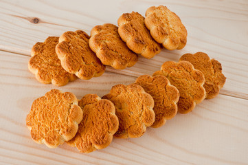 Tasty and beautiful cornflakes cookies among of corn flakes on a wooden table as background, top view