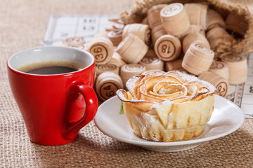 Board game lotto on sackcloth. Wooden lotto barrels in bag and game cards with cup of coffee and homemade cookie on plate.